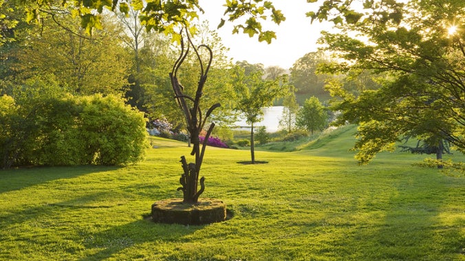 A spring garden, sculpture overlooking a pool.